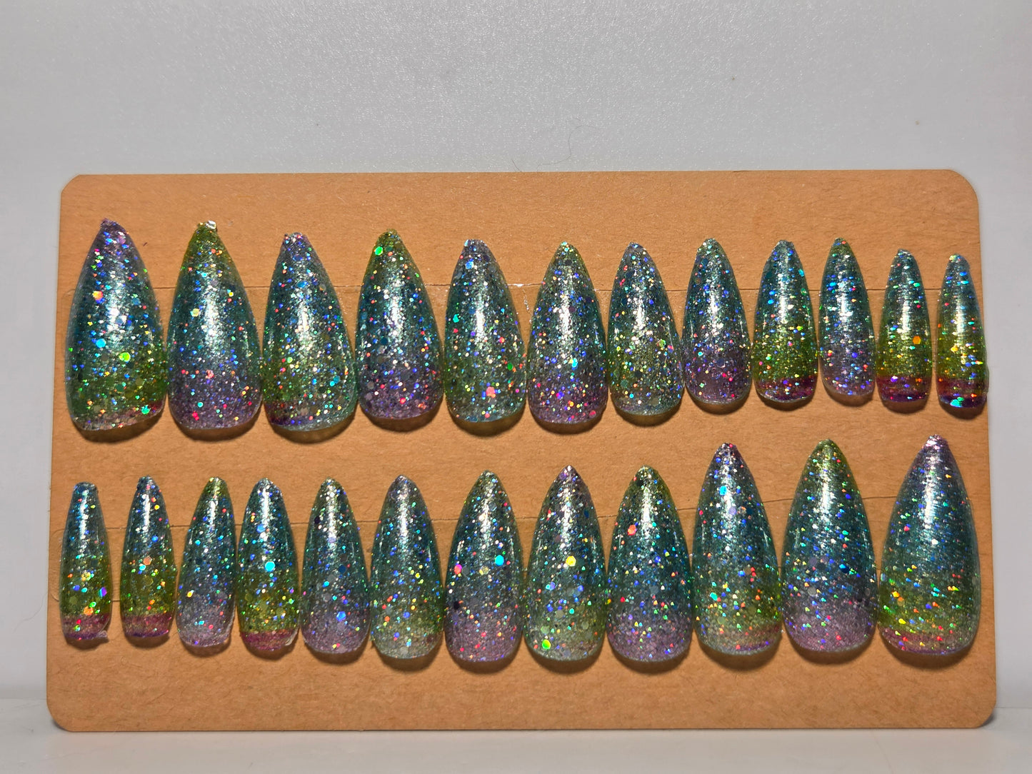 Set of glittery nail tips on a cardboard backing