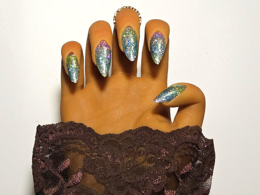Hand with glittery nail wrap wearing a brown lace sleeve against a white background