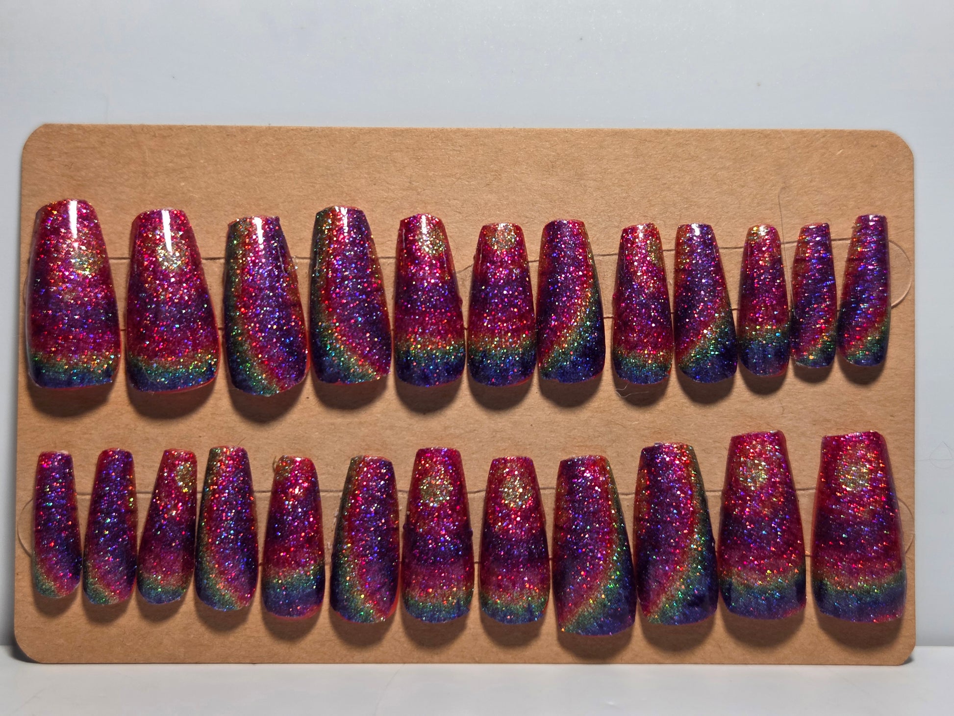 Set of glittery rainbow-colored handmade press on nails on a cardboard background