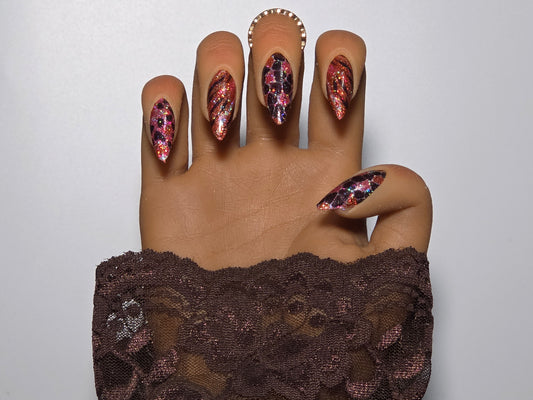 Hand with pink and black glitter handmade press on nails against a white background