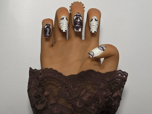 Hand with black and white Glow in the Dark nail wrap against a plain background