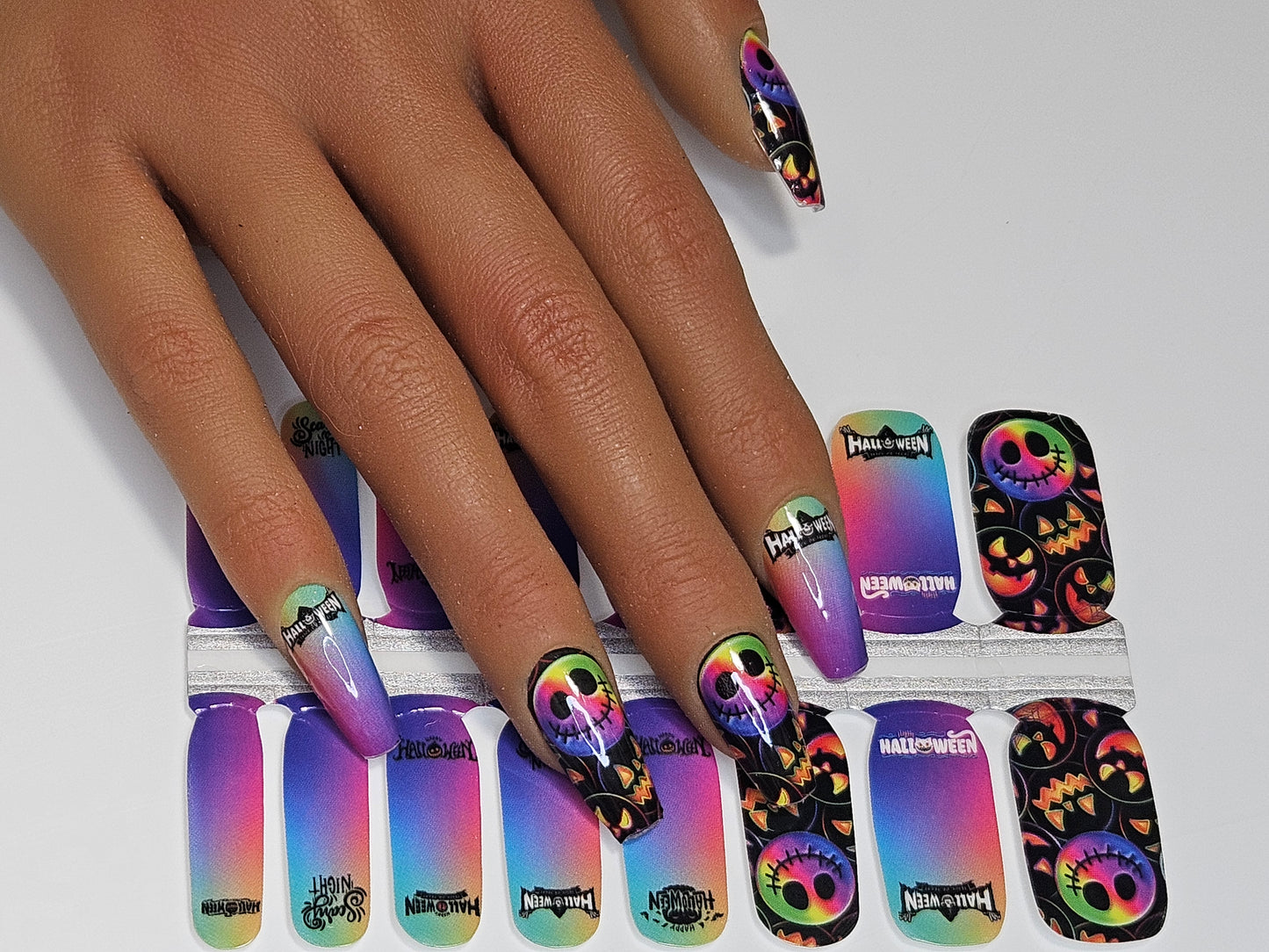 Nail wraps with colorful design shown on a hand against a white background