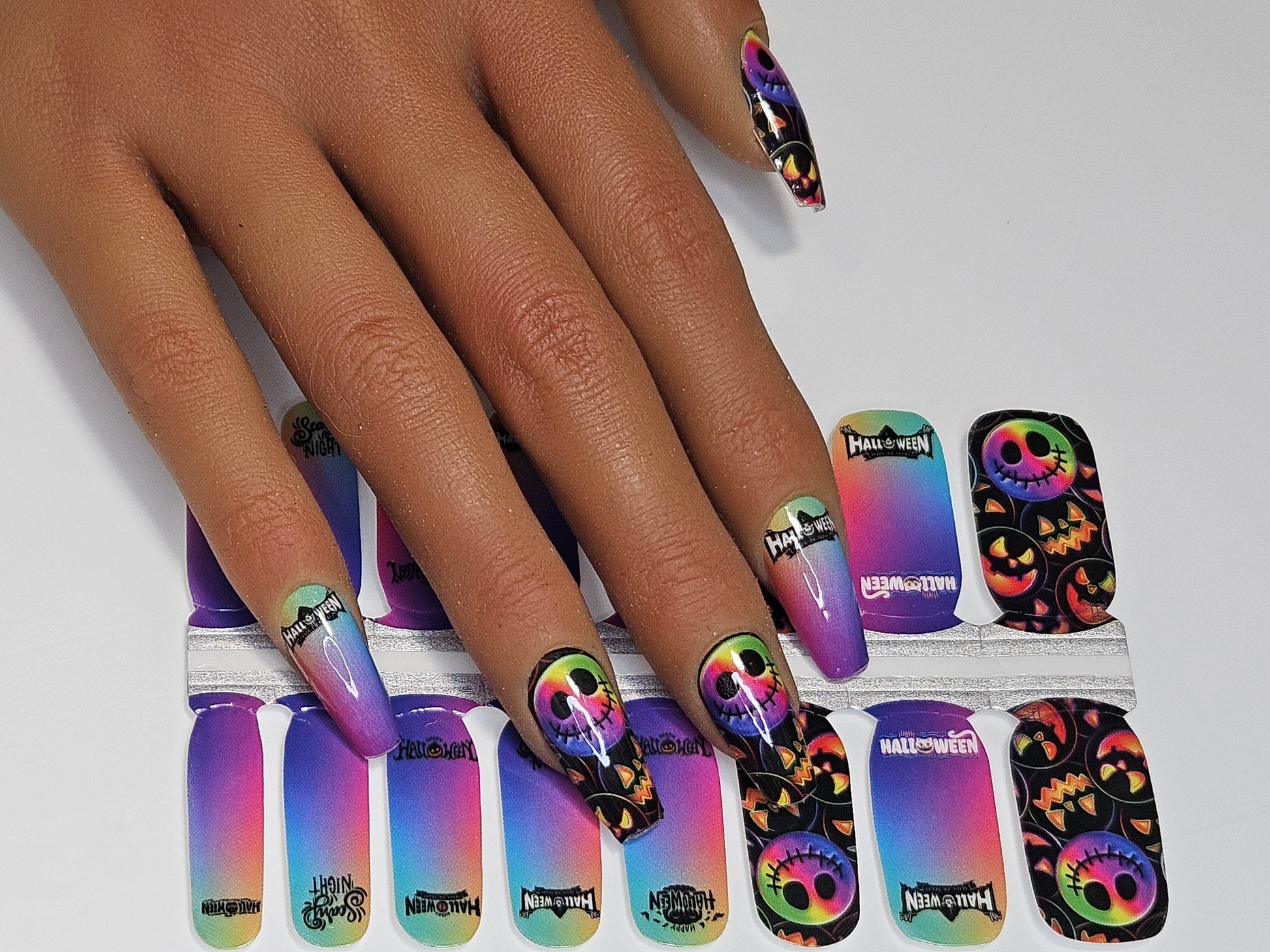 Nail wraps with colorful design shown on a hand against a white background