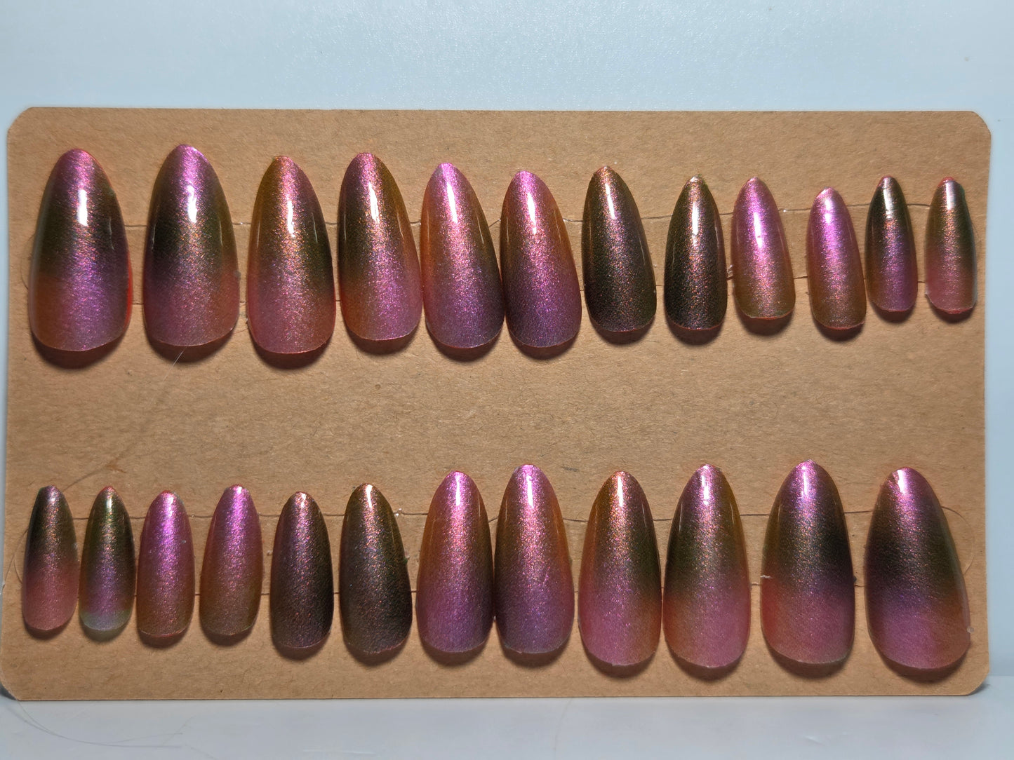 Set of aurora nail wraps over nail polish on a piece of cardboard backing