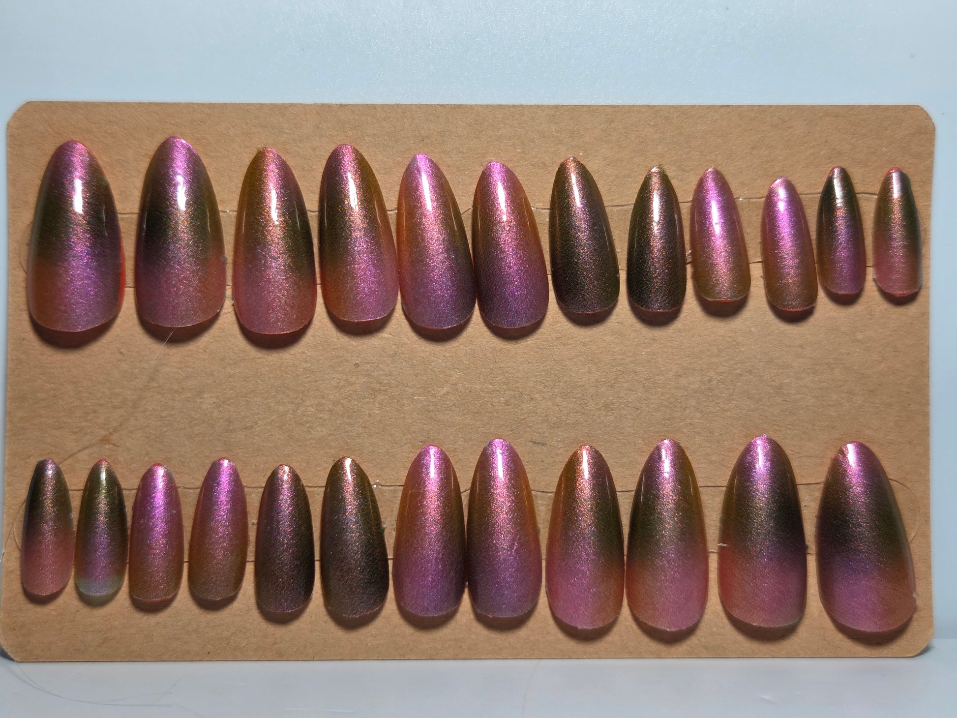 Set of aurora nail wraps over nail polish on a piece of cardboard backing