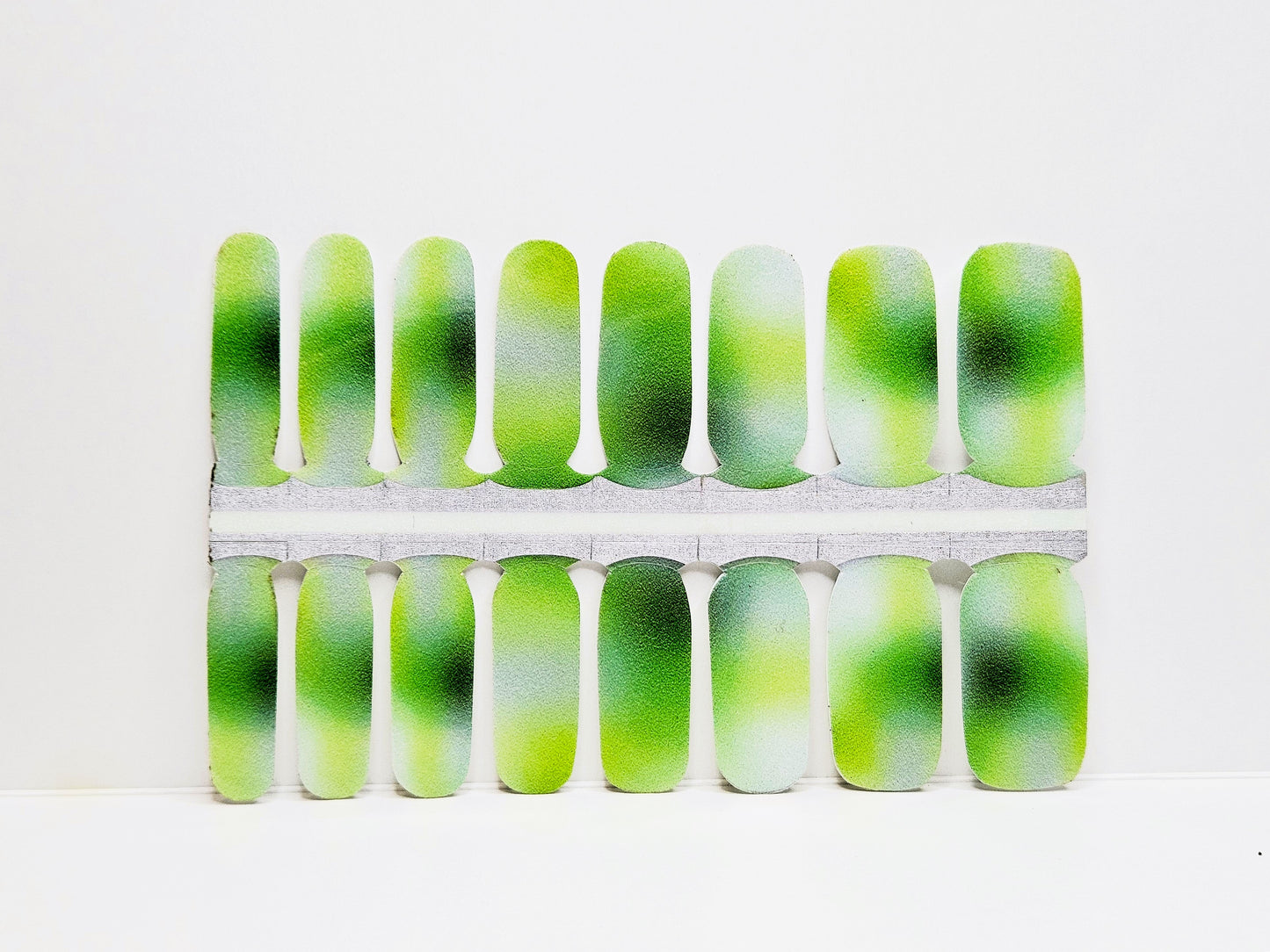 Green and white aurora nail wraps against a white background