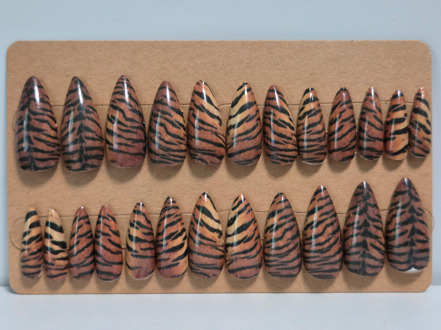 Set of tiger stripe patterned false nails on a cardboard display.