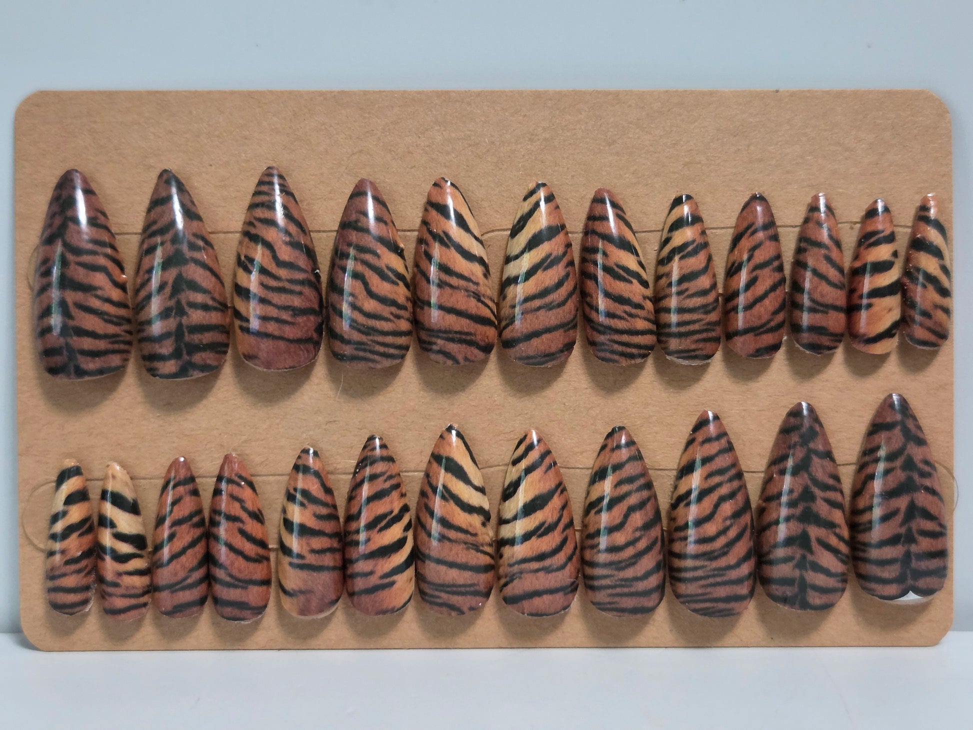Set of tiger stripe patterned false nails on a cardboard display.