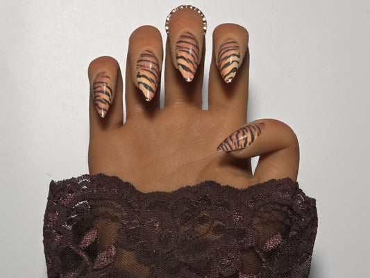 Hand with black lace sleeve and Tiger striped handmade press on nails against a white background