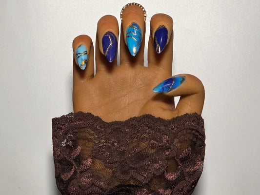 Hand with multi colored blue nail wraps against a white background