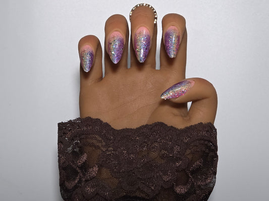 Hand with glittery multi colored handmade press on nails against a plain background